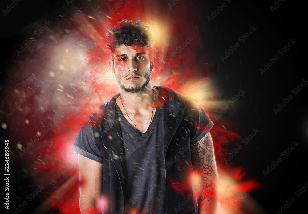 Confident bearded hipster man in casual outfit looking at camera in burning flame effect Confident bearded hipster man in casual outfit looking at camera in burning flame effect