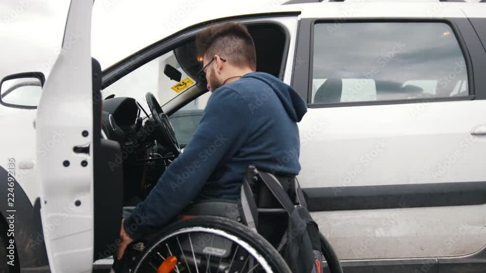Disabled man at wheelchair gets in car Disabled man at wheelchair gets in car