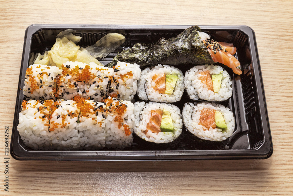 Japanese Cuisine: Tasty Uramaki , Futomaki and temaki served in the take-away box - selective focus Japanese Cuisine: Tasty Uramaki , Futomaki and temaki served in the take-away box - selective focus