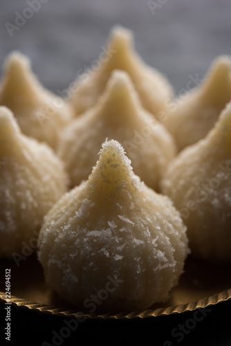 Sweet Modak made using coconut, khoya and sugar. Popular Maharashtrian recipe offered to lord Ganesha in Ganesh Festival. Served in a plate. Selective focus photo