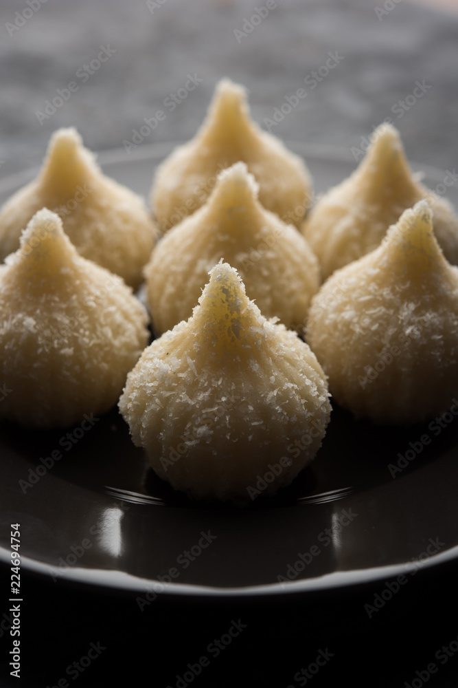 Sweet Modak made using coconut, khoya and sugar. Popular Maharashtrian recipe offered to lord Ganesha in Ganesh Festival. Served in a plate. Selective focus