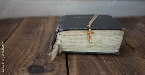 a golden cross on a bible on wooden background
