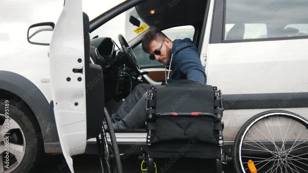 Disabled man in a car put together his wheelchair and picks it up in a car Disabled man in a car put together his wheelchair and picks it up in a car