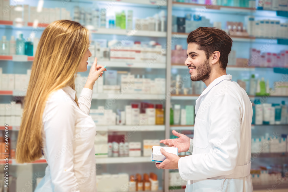 Experienced pharmacist counseling female customer in modern pharmacy