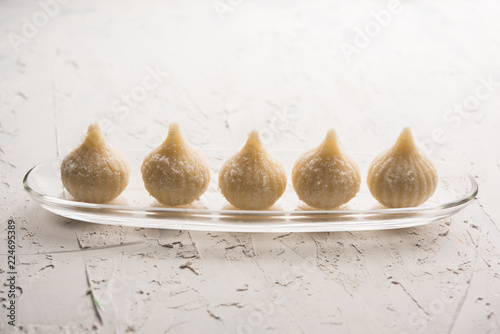 Sweet Modak made using coconut, khoya and sugar. Popular Maharashtrian recipe offered to lord Ganesha in Ganesh Festival. Served in a plate. Selective focus photo