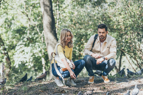 young couple with backpacks looking at pigeons in park © LIGHTFIELD STUDIOS