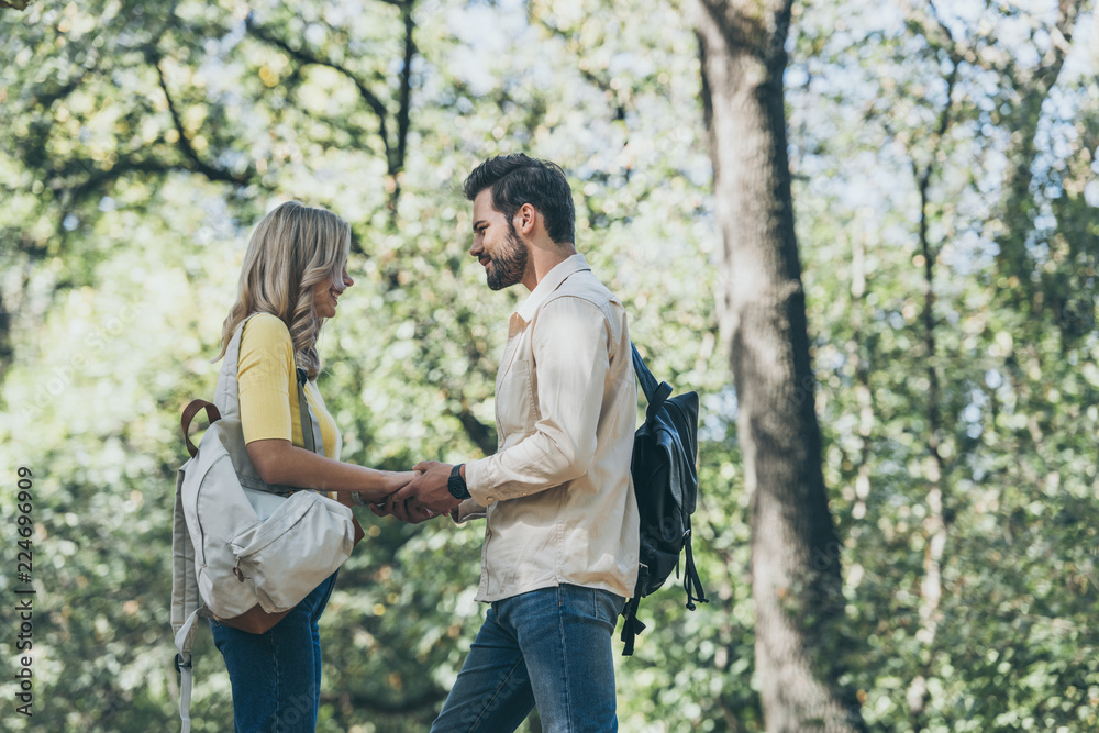 side view of young couple in love holding hands in park