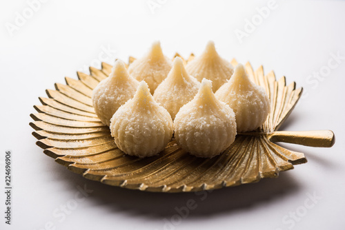 Sweet Modak made using coconut, khoya and sugar. Popular Maharashtrian recipe offered to lord Ganesha in Ganesh Festival. Served in a plate. Selective focus photo
