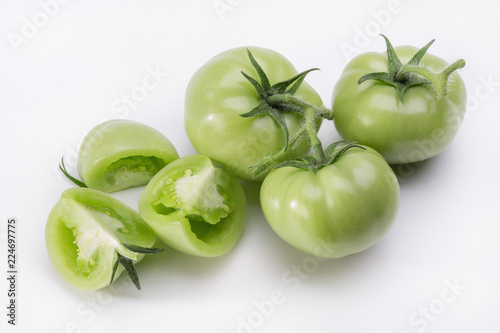  Set of fresh green tomatoes on light background with shadows.