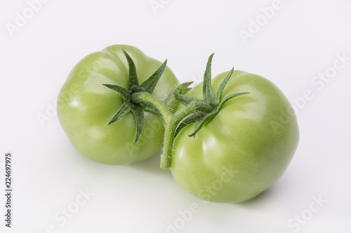 Green tomatoes on light background with shadows.