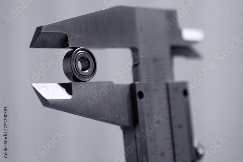 Measuring small bearing with vernier caliper. Monochrome close up image, shallow depth of field.