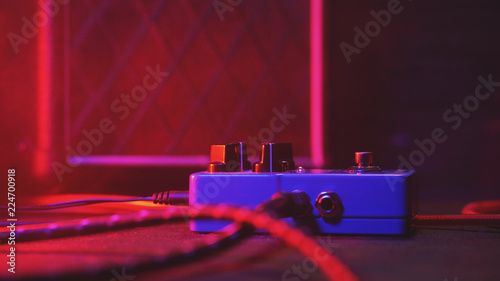 Extremely close up of button for effect electro guitar pedal. Red neon light in night club during show concert. photo