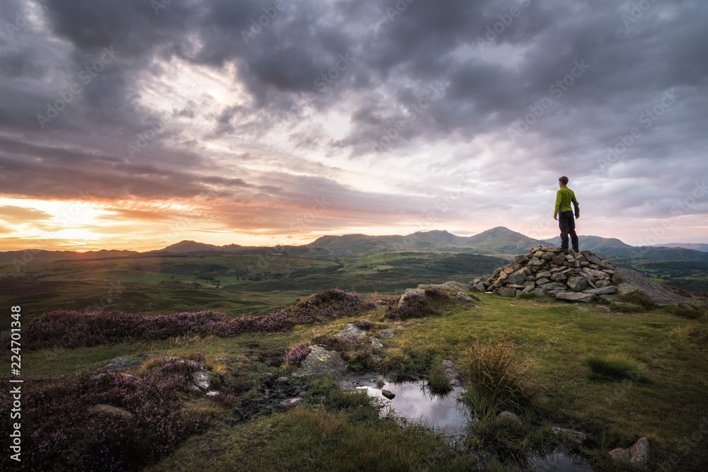 Strong hiker happy and enjoying sunset over Lake District England mountain background