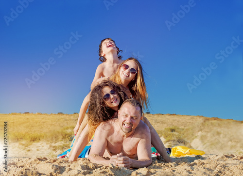 Happy family on sea beach at resort.A happy couple, married, husband and wife in the summer vacation. Holiday dream. With two kids. Mum and happy father. Lots of sunshine and sand.