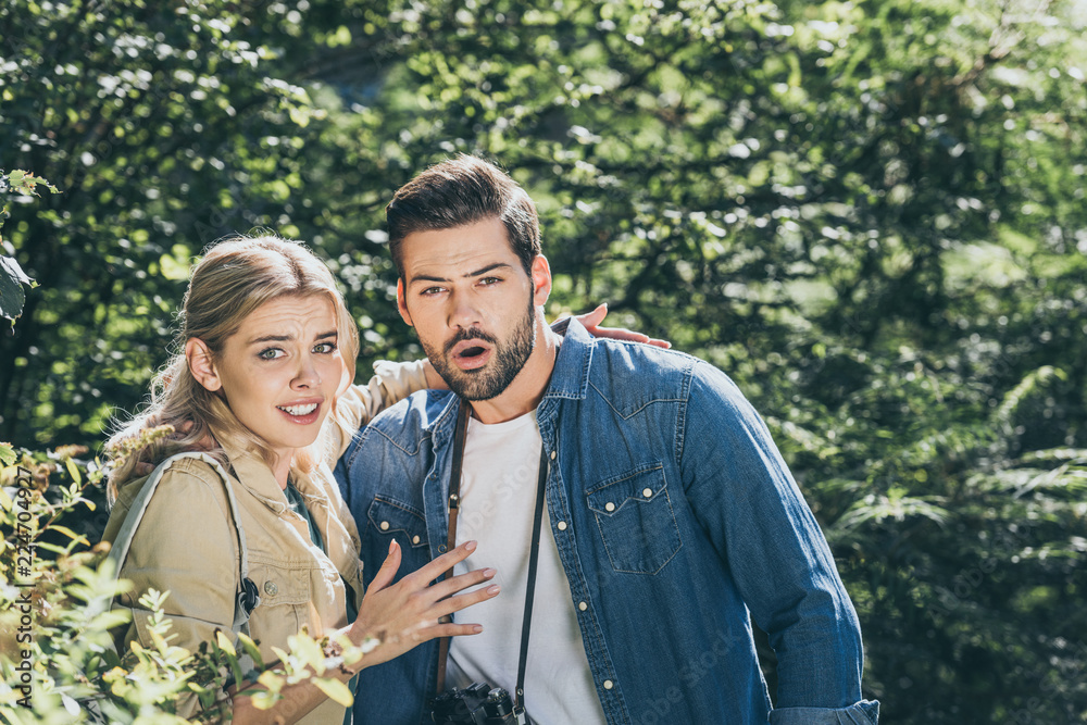 portrait of shocked couple of tourists with photo camera in park