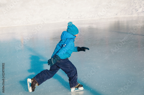 little boy skating on ice in winter nature