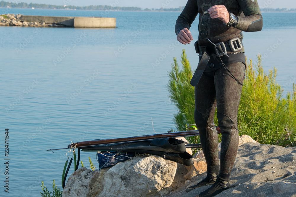 Crop view of scuba diver adult man on a seashore with spearfishing gear  (fins, speargun), space for text Stock Photo