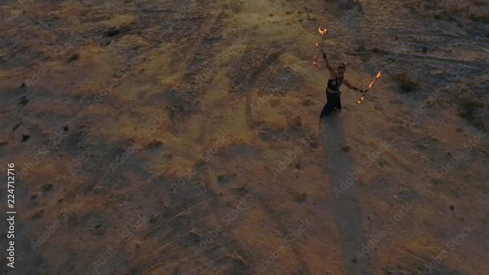 The woman is spinning around with burning fire balls