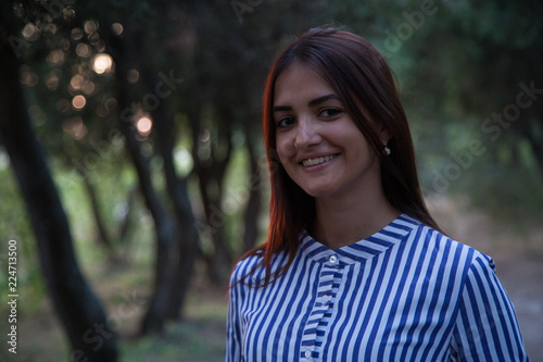 young pretty girl smiling and looking at camera at sunset in the park
