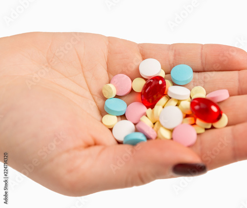 Multicolored pills in female hand, close-up, isolated on white background