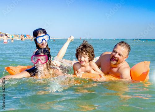 Happy father and three children have fun swimming in the sea on a vacation on the beach