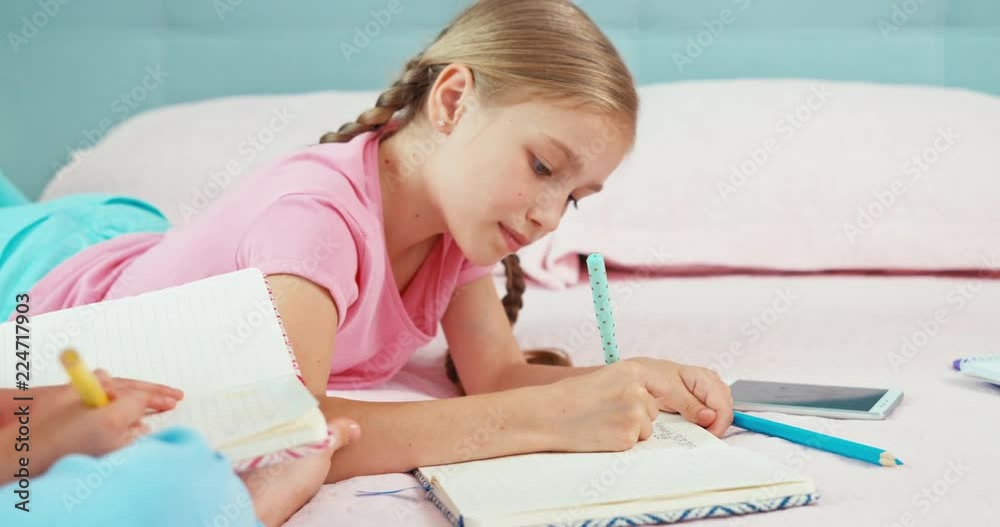 Two sisters are on the bed and something drawing in their notebooks Two sisters are on the bed and something drawing in their notebooks