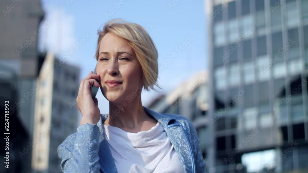 Beautiful business woman receives a call in front of the office building Beautiful business woman receives a call in front of the office building