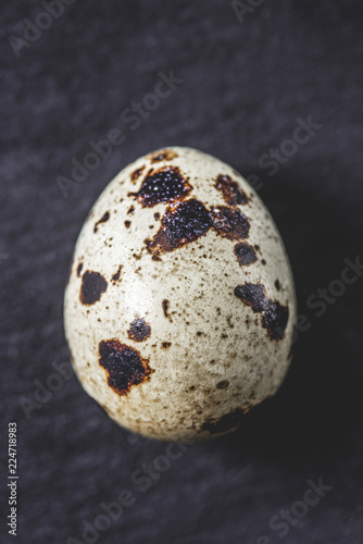 top view of organic unshelled quail egg on black, close-up view