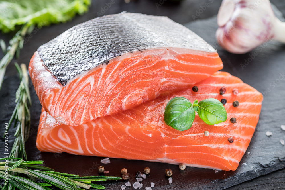 Fresh salmon fillets on black cutting board with herbs and spices. Fresh salmon fillets on black cutting board with herbs and spices.