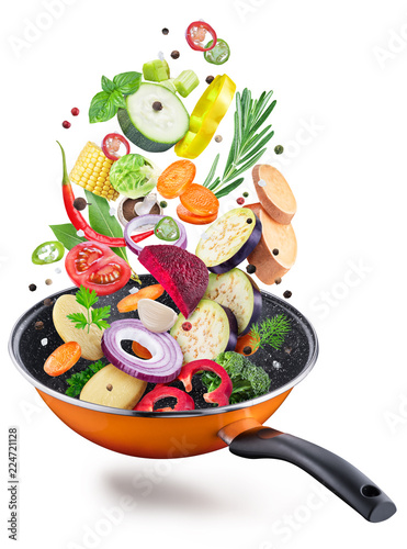 Flying fresh vegetables and spices over a pan. File contains clipping path.