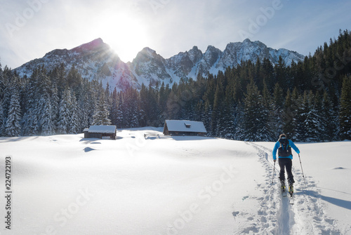 Ski mountaineer reaches alpine hut in the midst of mountain range during backcountry skiing.