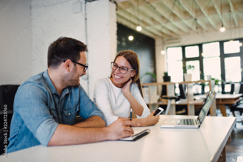 Two smiling colleagues talking in modern open space office. Two smiling colleagues talking in modern open space office.