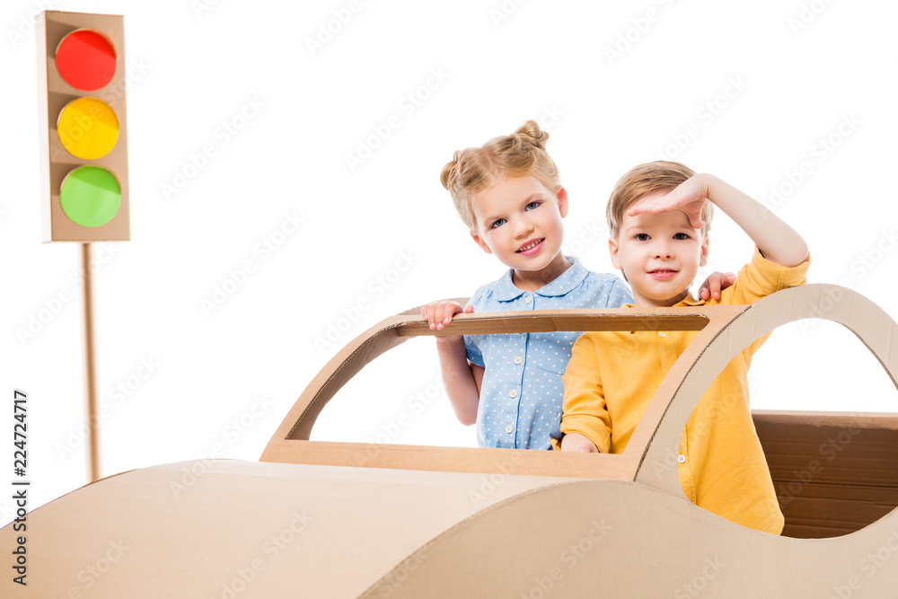 siblings playing with cardboard car and traffic lights, isolated on white siblings playing with cardboard car and traffic lights, isolated on white