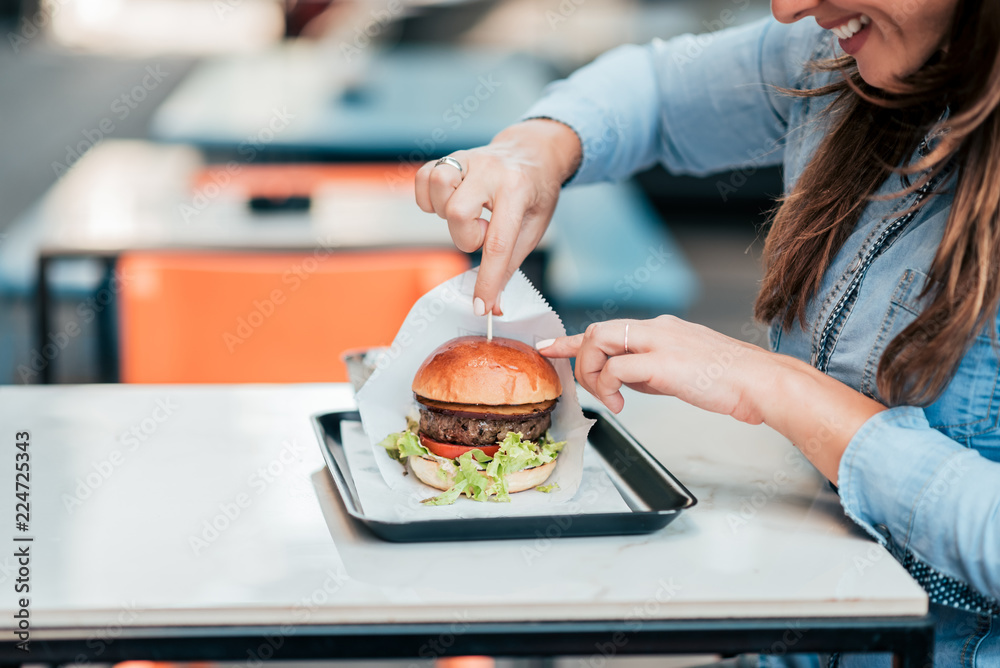 Close-up image of young woman eating hamburger.