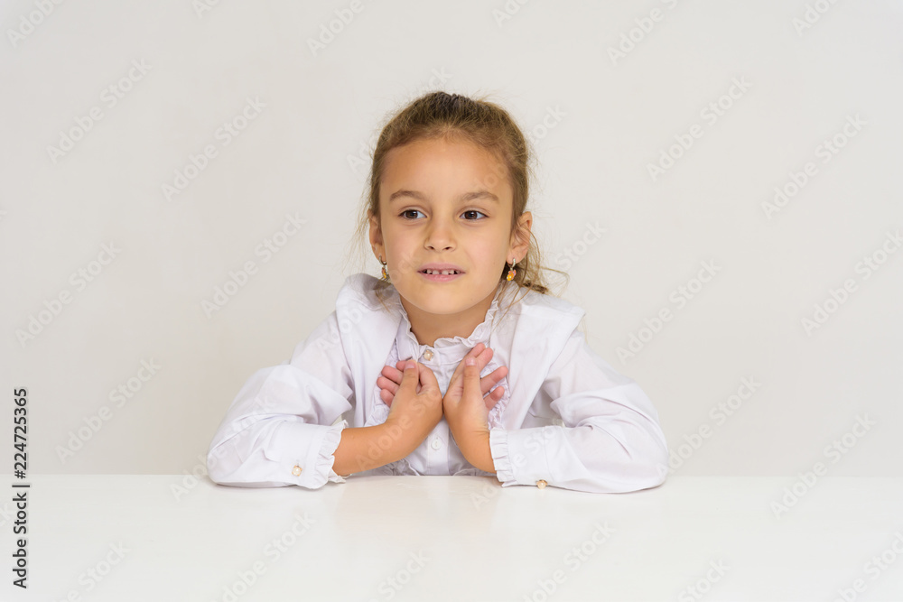 Portrait of a cute baby girl on a white background at the table. Portrait of a cute baby girl on a white background at the table.