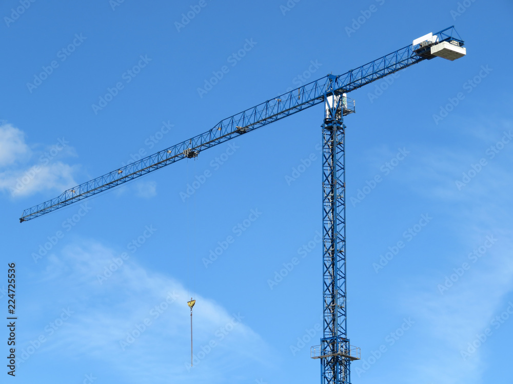 Construction crane against blue sky with white clouds