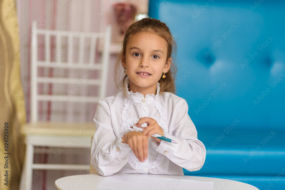 A cute little girl is sitting at a table drawing and telling. A cute little girl is sitting at a table drawing and telling.