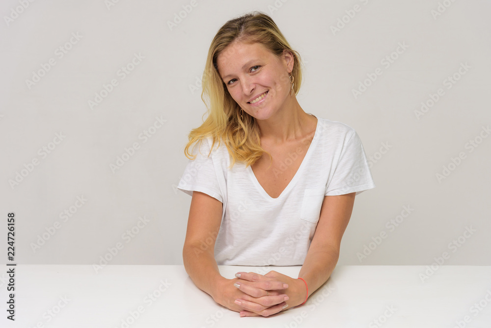 Fototapeta premium Portrait of a beautiful girl on a white background at the table.