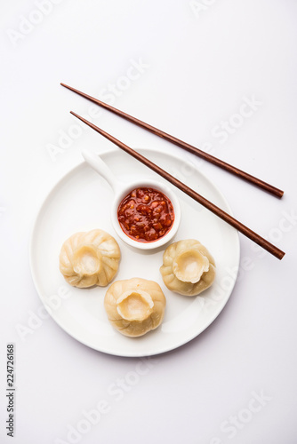 Dumpling momos food from Nepal or Ladakh served with red chilli chutney over moody background. Selective focus