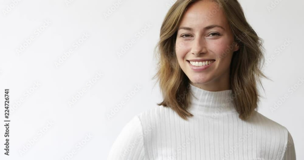 Young brunette woman on white background smiles and laughs to the camera - 4k 25fps