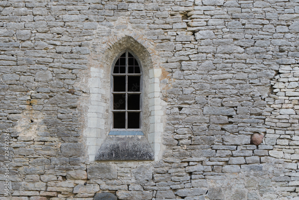 Window in the stone wall of an ancient monastery destroyed during the Livonian War in the Middle Ages