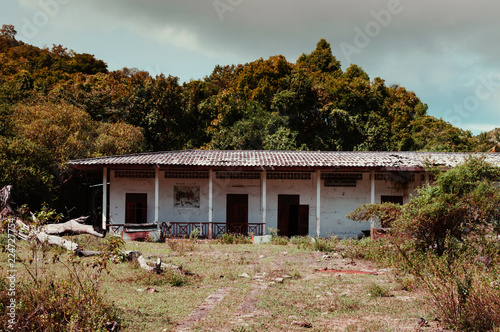 Abandoned devastated school in grass field on cloudy day © PixHound