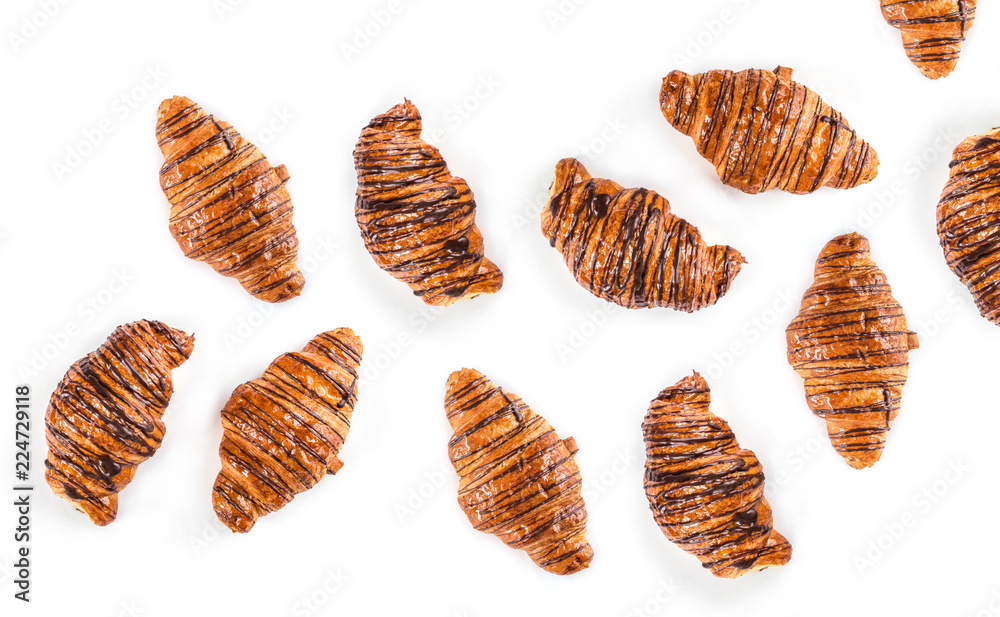 Fresh croissants with hot chocolate chaotically arranged on a white background, top view