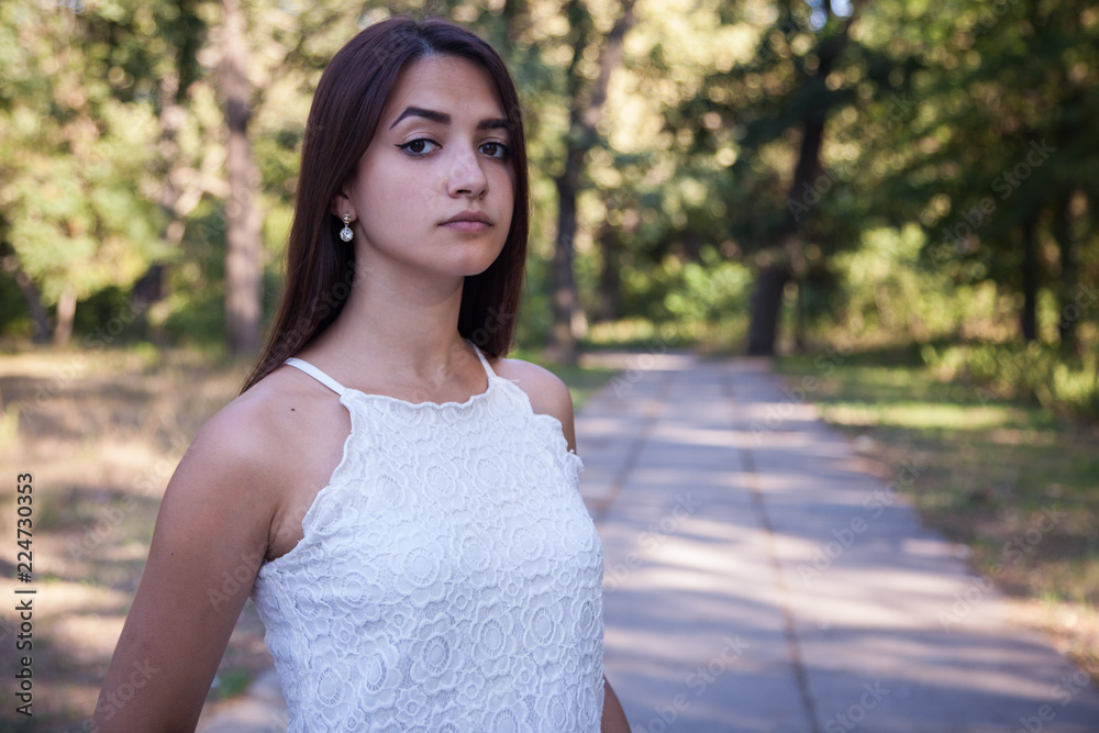 serious cute woman standing in the green park