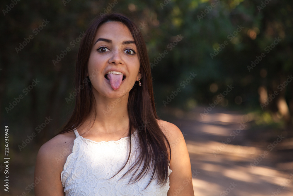 young cute woman showing to standing in the green park young cute woman showing to standing in the green park