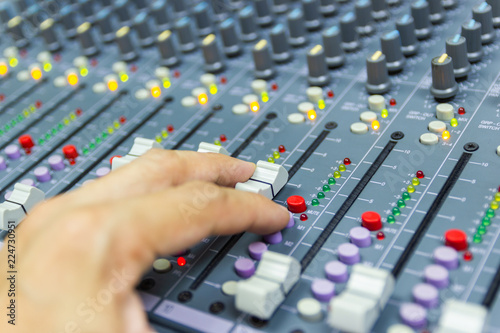 Close-up hand of man control Mixing Console of a big HiFi system The audio equipment, control panel of digital studio mixer.  