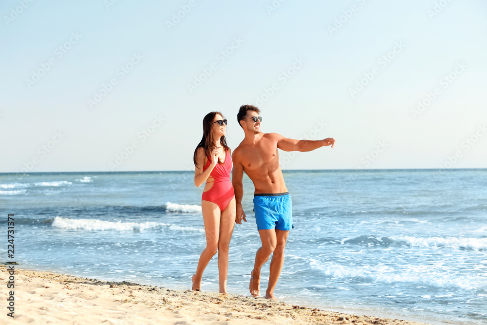 Happy young couple walking together on beach