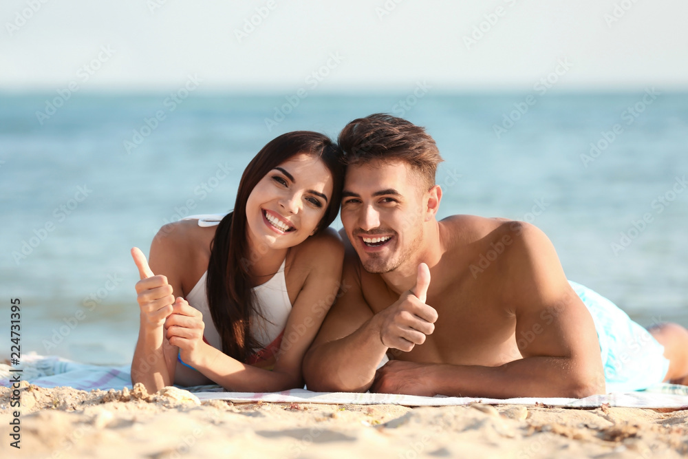 Fototapeta premium Happy young couple lying together on beach