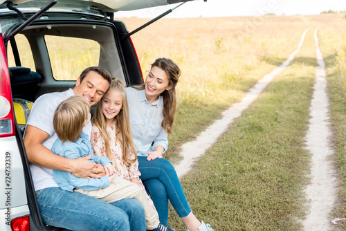 beautiful young family spending time together in field while having car trip