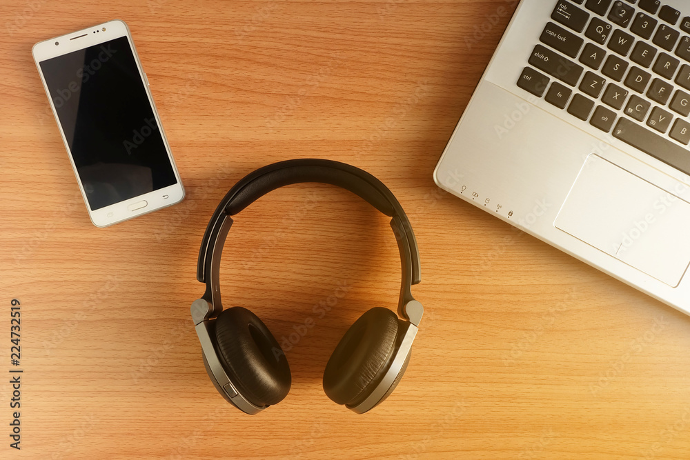 Over-Ear Headphone and smart phone with laptop on wooden floor,used electronics gadgets, Top view Over-Ear Headphone and smart phone with laptop on wooden floor,used electronics gadgets, Top view